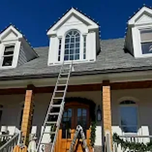 Residential home during roofline Christmas light installation with ladder access
